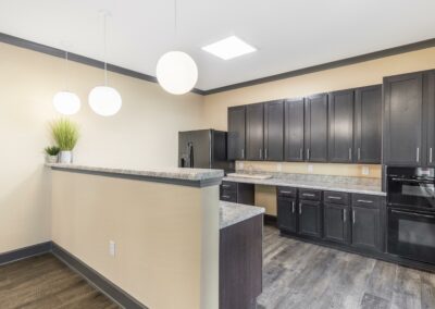 Island view of Goodnight Commons apartment kitchen with granite countertops and black appliances
